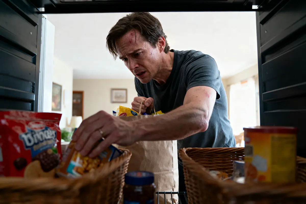 Un homme cherche de la nourriture dans un garde-manger, entouré de paniers et de produits divers.